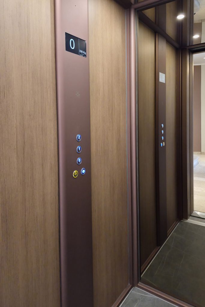 Home lift Eltec Lift HLB elettrico integrato in atrio di villa storica del 1700, con struttura AU e finiture armonizzate; tecnologia elegante e discreta che rispetta il contesto storico. Dettaglio della pulsantiera a tutt'altezza e specchio a grandezza parete.